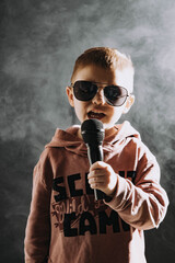 Chłopiec śpiewa do mikrofonu rocka i bluesa, studio nagrań, mały wokalista, śpiew, muzyka,  - obrazy, fototapety, plakaty
