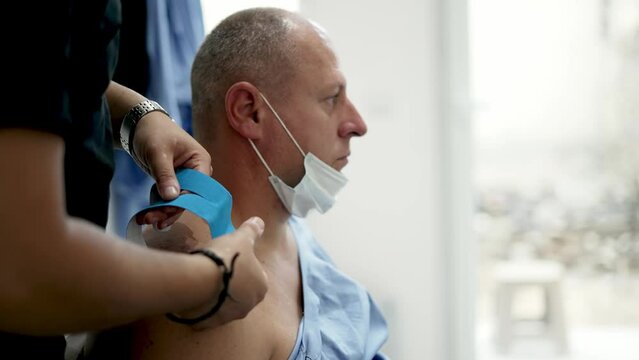 Kinesiology taping. Physical therapist applying kinesiology tape to patient shoulder