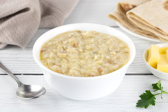 Traditional Armenian porridge - harissa with chicken, butter and lavash bread. White wooden background. Top view.