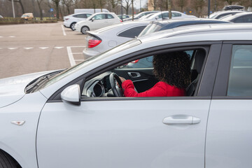 Obraz na płótnie Canvas African american woman in red coat driving with a white car out of the parking