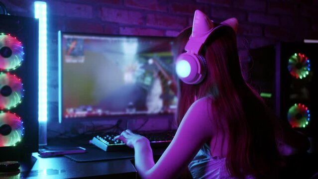Cute gamer girl playing shooter game on her PC