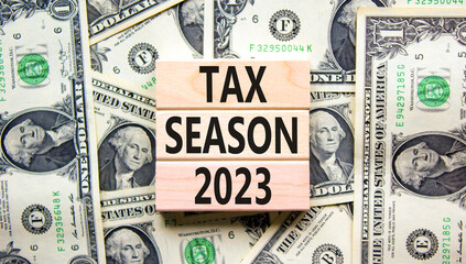 Tax season 2023 symbol. Concept words Tax season 2023 on wooden blocks on a beautiful background from dollar bills. Business Tax season 2023 concept. Copy space.