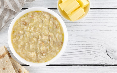 Traditional Armenian porridge - harissa cooked with chicken, wheat and butter. White wooden background. Top view. Copy space.