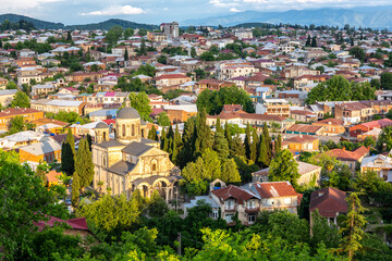 Fototapeta na wymiar Cityscape of Kutaisi with Bagrati Cathedral and colorful residential buildings and houses during sunset.