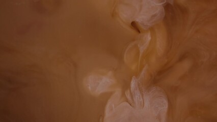 Milk pouring into coffee slow motion. Coffee and milk clouds closeup.