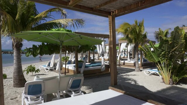 Beach cabanas overlooking the Caribbean Sea. Relax in the shade. Beach, sand, umbrellas, loungers, curtains, palm trees, beach beds. Adrenaline Beach, Labadee, Haiti private resort by Royal Caribbean.