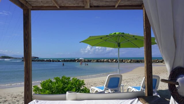 Beach cabanas overlooking the Caribbean Sea. Relax in the shade. Beach, sand, umbrellas, loungers, curtains, palm trees, beach beds. Adrenaline Beach, Labadee, Haiti private resort by Royal Caribbean.