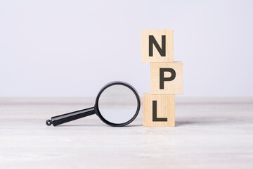 concept Non Performing Loans or NPL. text on wooden cubes under a magnifying glass.