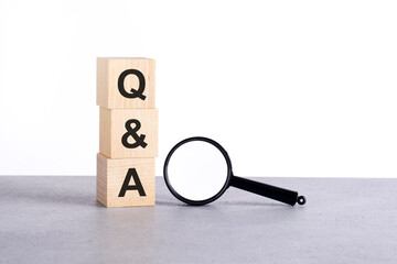 Q qand A - Question and Answer - text wooden cube blocks and magnifying glass on grey table