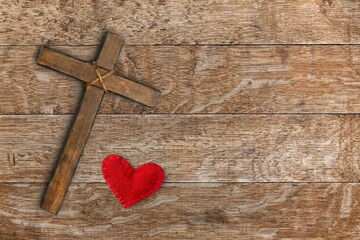 Red heart and wooden cross on desk