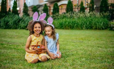 A two girls during Easter egg hunt and putting Easter eggs in baskets