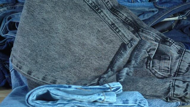 Folded jeans fall in slow motion onto a pile of denim pants.