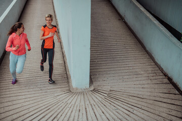 Two women in sports clothes running in a modern urban environment. The concept of a sporty and healthy lifestyle