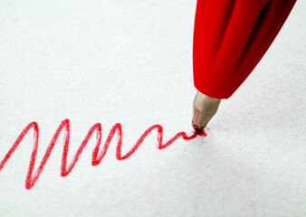 A red line with a red pen on white paper. Close up. Macro
