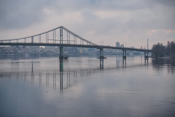 Pedestrian bridge with a bike path across the Dnieper River in the center of Kyiv, on a cloudy spring day