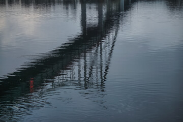 Reflection of a pedestrian bridge in the water surface of the Dnieper River in the center of the city of Kyiv, on a cloudy spring day