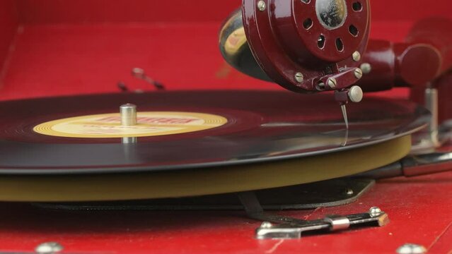 Hand turns on a vintage vinyl record and vinyl record is spinning. Vinyl playing. A man putting a shellac gramophone record at home. Close-up. Close-up of a man starting a record player and a vinyl