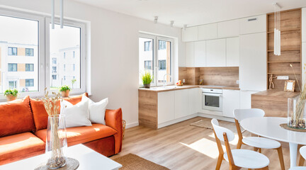 Kitchen interior with white furniture in scandinavian design and dining room with table and chairs. Interior  with wooden floor and window in new apartment in luxurious style.