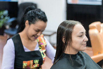 Latina woman cutting young girl's hair.