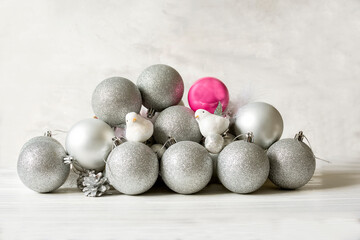 Christmas tree Christmas New Year silver and pink balls and decorative birds on a light concrete background.