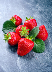 Reife rote Erdbeeren aus biologischem Anbau angeboten als close-up auf einem grauen Board mit Textfreiraum
