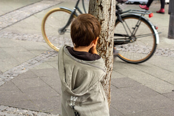 child playing hide and seek in front of an old bycicle