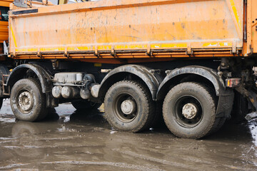 Tipper truck driving construction site. Muddy ground rainy day. Heavy vehicle. Dumper lorry. Big rubber tyres.