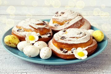 Delicious fresh pastries with icing sugar on a blue plate with chocolate sweet eggs for Easter gift