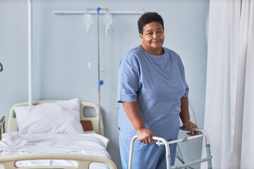 Portrait of black senior woman standing with support in hospital room and looking at camera, copy...