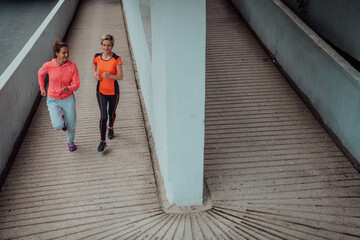 Two women in sports clothes running in a modern urban environment. The concept of a sporty and healthy lifestyle