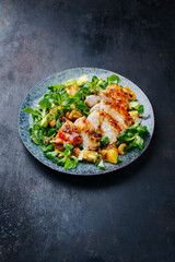 Traditionaler deutscher Feldsalat mit Hähnchen Brust, Obst und Cashewnüsse serviert mit würziger süß sauer Sauce als close-up auf einem Nordic Design Teller mit Textfreiraum