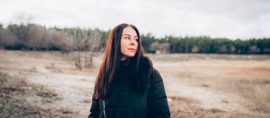 Portrait of young smiling brunette woman in winter jacket looking at camera