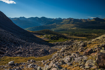 Mountain landscape with foreground rocks and distant peaks in sun rays