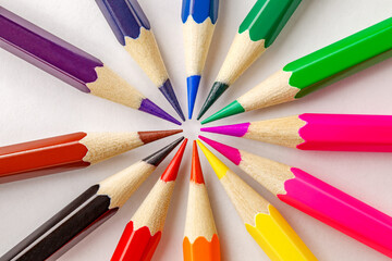 Colored pencils arranged in circle on white background, close-up full depth of field