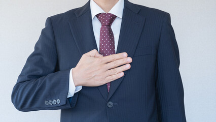 安心・おまかせポーズ｜スーツ姿で胸に手を当てる男性