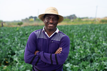 Portrait of man farmer standing in farm field on sunny spring day