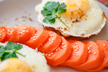Fried eggs with meat cutlets and carrots with spices and sesame seeds close-up selective focus