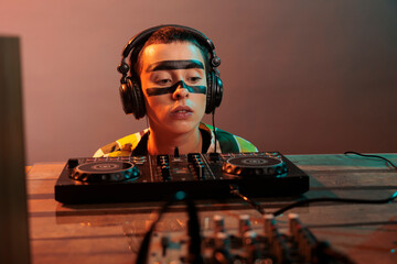Female artist looking at dj turntables in studio, preparing to mix techno music and have fun at...