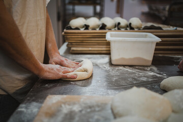 Professional baker preshpaing bread dough during bread making proccess in bakery - obrazy, fototapety, plakaty
