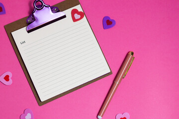 Women's pink office desk. Notepad, pen, stickers on a pink background. Flat lay, top view, copy space, banner