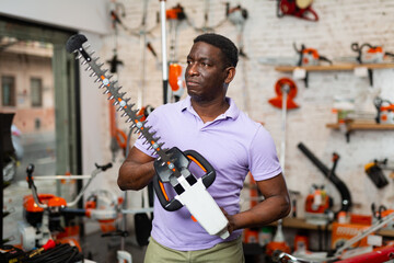 Adult serious man with an brush cutter in hardware store