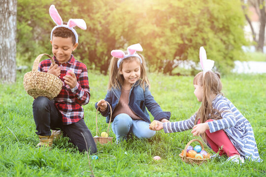 Little children gathering painted eggs in park. Easter hunt