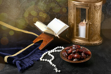 Naklejka na ściany i meble Plate with dates and prayer beads, Quran book and fanous lamp on dark background
