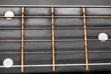 Frets on guitar neck and white dots close-up, selective focus
