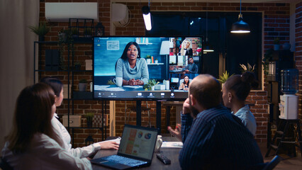 Remote team business meeting, coworkers talking in videocall at night time. Diverse people chatting...