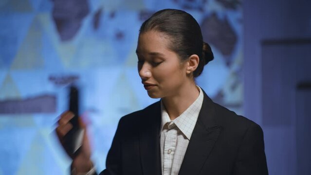 A young woman, manager, administrator at the admin desk, talks on the work phone, smiles, lets the visitor through. Reception, hotel, business center.