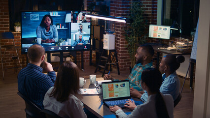 Company sales statistics discussion in remote business meeting videocall, employees team talking in videoconference at night time. Office workers chatting in teleconference - obrazy, fototapety, plakaty