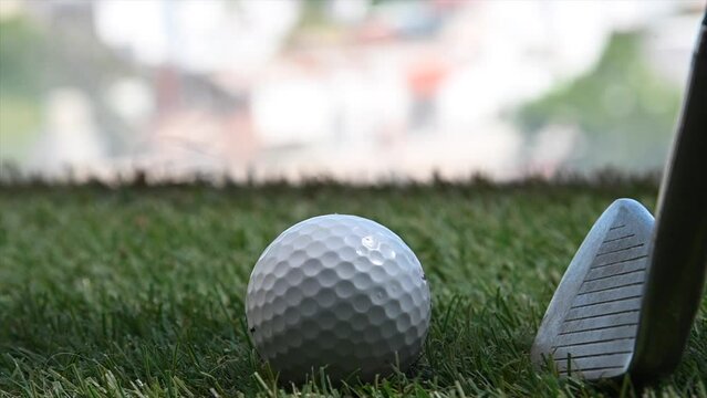 close up of golf ball and putter near office window with city in background