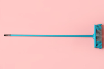 Blue cleaning broom on pink background