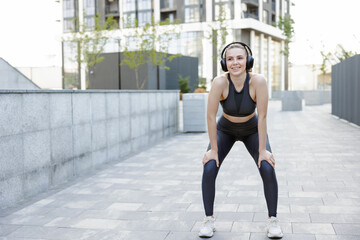 Fototapeta na wymiar Smiling female runner in sportswear catching breath, while jogging outdoors.